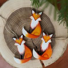 three orange and white foxes sitting on top of a piece of wood