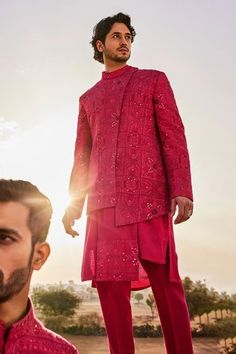 a man in a red outfit standing next to another man with his hand on his hip