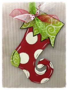 a red and green christmas stocking hanging from a wall with a bow on it