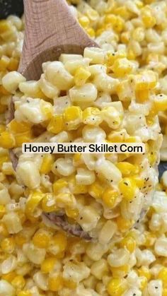 a wooden spoon is scooping corn from a skillet