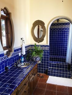 a bathroom with blue tile and wooden cabinets