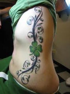 a woman's stomach with shamrock tattoos on it