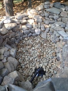 a pile of rocks sitting next to a forest filled with trees