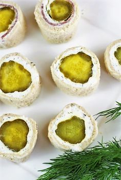 small crackers with olives and cheese are on a white plate next to a sprig of rosemary