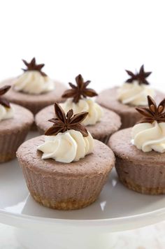 chocolate cupcakes with white frosting and cinnamon stars on top are sitting on a plate