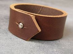 This beautiful leather bracelet was made using high quality leather and will wear wonderfully with age. The leather cuff is provided with a strong silvery rivet, for a quick and easy closure.Guidelines : ● 2.2 cm (7/8") wide● 3 mm thick ●15 cm (approx 6") long It will definitely add a sweet touch to your outfit! With it's simple design, this boho bracelet would also make an amazing 3rd anniversary gift ! ***Thank you for visiting AdSaggitam! :) Adjustable Leather Bracelet With Snap Closure, Adjustable Leather Rivets Bracelet, Leather Jewelry With Rivets For Gifts, Leather Jewelry With Rivets As A Gift, Leather Cuff Bracelet With Rivets, Adjustable Cuff Bracelet With Rivets As Gift, Classic Brown Leather Cuff Bracelet, Mens Leather Cuff Bracelets, Bracelet Boyfriend