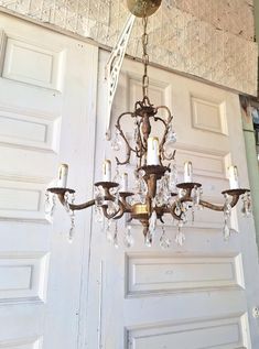 a chandelier hanging from the ceiling in front of a door with white doors