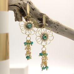 EMMA Earrings These elegant and bohemian long flower earrings are adorned with dazzling green and cream crystals wrapped in golden copper wire. They're perfect for adding a sophisticated contrast and a touch of sparkle and elegance to any outfit. Crafted from high-quality materials, they're ideal for special occasions or for adding a bit of glamour to your everyday look. The length of the earrings adds sophistication, while the crystals catch the light beautifully. Perfect for weddings, parties, Bohemian Dangle Flower Earrings For Pierced Ears, Bohemian Wire Wrapped Flower Earrings, Bohemian Flower Drop Earrings With Dangling Beads, Bohemian Green Earrings With Dangling Charms, Bohemian Flower Earrings With Dangling Beads, Green Bohemian Earrings With Dangling Charms, Bohemian Gold Beaded Flower Earrings, Bohemian Green Flower Earrings With Dangling Beads, Handmade Bohemian Dangle Flower Earrings