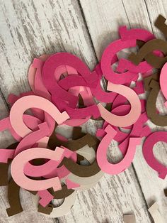 pink and brown cut out letters sitting on top of a white wooden table next to scissors