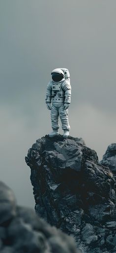 an astronaut standing on top of a rocky cliff