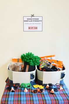 two buckets filled with toys sitting on top of a plaid tablecloth covered table