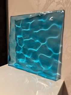 a blue glass block sitting on top of a white counter next to a wallpaper