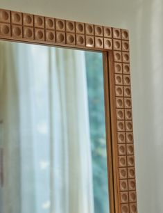 a mirror that is sitting in front of a window with the reflection of a curtain behind it