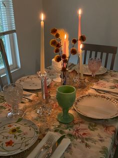 a table set for dinner with candles and dishes