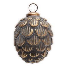 an ornate black and gold ornament hanging from a hook on a white background