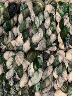 several skeins of green and white yarn are stacked on top of each other