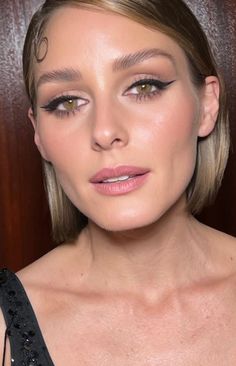 a woman with blonde hair and smoky makeup looks at the camera while wearing a black dress