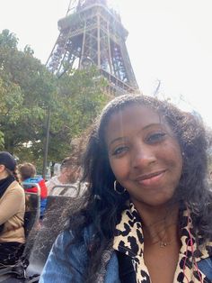 a woman is sitting in front of the eiffel tower, smiling for the camera