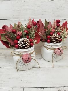 two white mason jars filled with red berries and pine cones