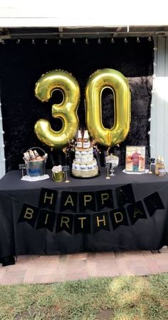 a black table topped with a cake covered in gold foil balloons and an 80th birthday sign