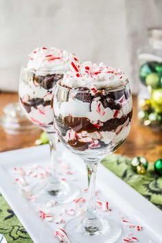 two glasses filled with ice cream and candy canes on top of a white tray