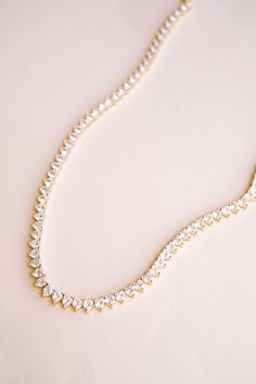 Introducing our gold Queen's Heart Tennis Necklace. This gold dainty choker is the perfect way to add a little romance to your style! Featuring a row of heart-shaped cubic zirconia stones set in a delicate 14k gold-plated design, this necklace brings a touch of royal charm to any outfit. Ideal for casual days, date nights, weddings, bridesmaid gifts, or glamorous evenings, the Queen's Heart Necklace makes every look feel extra special. It's a chic and versatile piece you'll reach for time and time again! ----------------------  NECKLACE FEATURES ◊ Material: Brass, White Cubic Zirconia ◊ Dimensions/Size: 14" with 2" Extender ◊ Finish: 14k Gold Plating ----------------------  PACKAGING ◊ We do the gift-wrapping for you! All jewelry comes packaged in our custom, foiled pressed gift boxes.  -- Gold Tennis Necklace, Tennis Choker Necklace, Diamond Necklace Gold, Dainty Choker, Bridal Jewelry Collection, Dainty Gold Necklace, Gold Choker Necklace, Bridesmaid Bracelet, Birthstone Gifts