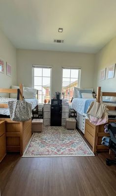 a dorm room with bunk beds, desks and drawers on the floor in front of two windows