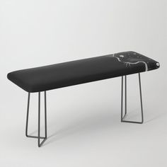 a black bench with metal legs and a cat design on the backrest, in front of a white background