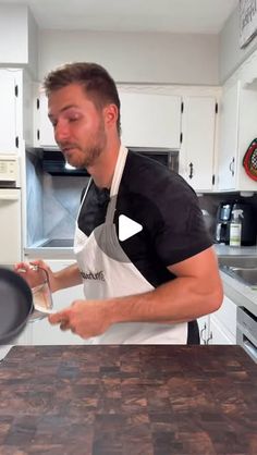 a man standing in a kitchen holding a frying pan