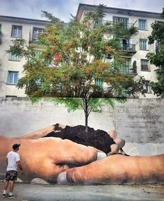 a man standing in front of a giant hand with a tree growing out of it