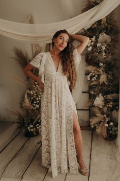 a woman standing in front of a white backdrop wearing a lace dress and high heels