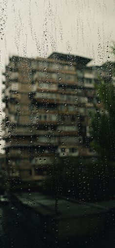 rain drops on a window with a building in the background