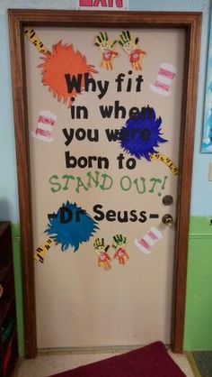 a door decorated with handprints and writing on the front, behind which is a dr seuss quote