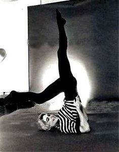 a woman doing a handstand on the floor with her feet up in the air