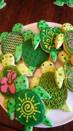 some decorated cookies are on a plate with green turtle decorations and pink flowers in the center