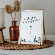 a table number sitting on top of a table next to a vase with flowers in it