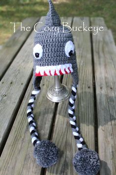 a crocheted shark wine glass holder on a picnic table with grass in the background