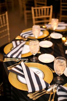 the table is set with black and white striped napkins, gold rimmed plates, and silverware