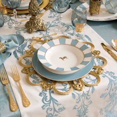 a blue and white table setting with gold accents