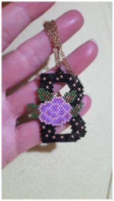 a hand holding a beaded key chain with a flower in the shape of a heart