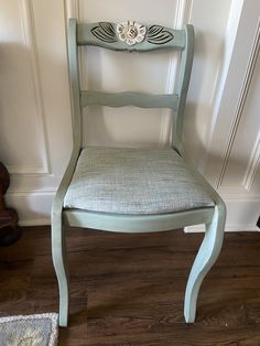 a green chair sitting in front of a wall with a flower on the back of it