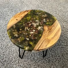 a wooden table with moss and rocks on it sitting on carpeted area next to wall