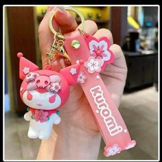 a person holding a pink keychain with a cartoon character on it's side