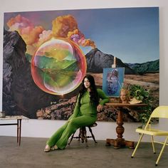 a woman sitting on a chair in front of a painting