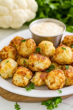 a white plate topped with tater tots next to a bowl of ranch dressing