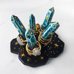 a bunch of rings sitting on top of a black stand with gold stars and pearls