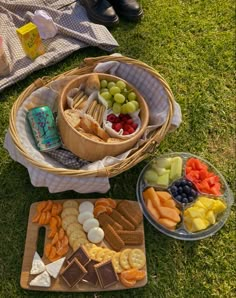 an assortment of snacks are arranged in baskets on the grass next to a picnic blanket