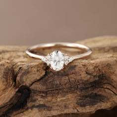 a white diamond ring sitting on top of a piece of driftwood with the background