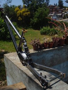 a large metal object sitting on top of a cement block next to potted plants