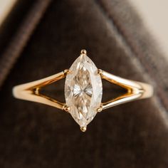 a ring with a pear shaped diamond in it's center, sitting on top of a velvet case